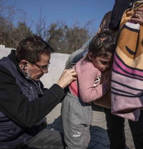imagen de un padre refugiado dando el biberón a su bebé